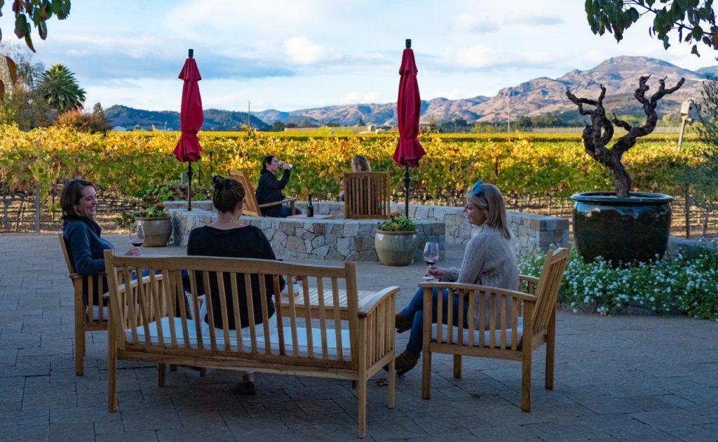 Several guests wine tasting on the patio of Robert Biale Vineyards with a a view of the hills. 