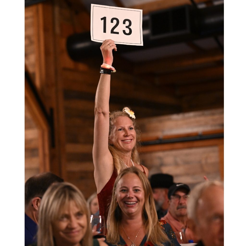 Jenah Victor bidding at auction. She is a returning supporter who celebrated her 50th birthday at Project Zin while continuing her philanthropic efforts, including co-running KidsServe with her son.