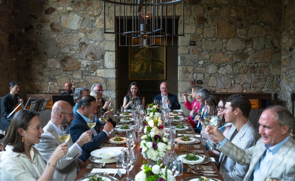 Guests raising their wine glasses for a photo during Auction Napa Valley dinner. 