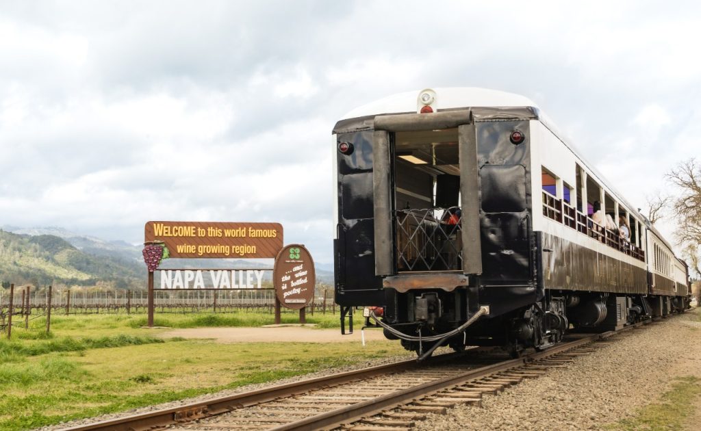 Napa Valley Wine Train passing iconic welcome sign. 